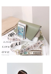 Detail of crossbody bag with green flap and patterned wide strap showing size with phones