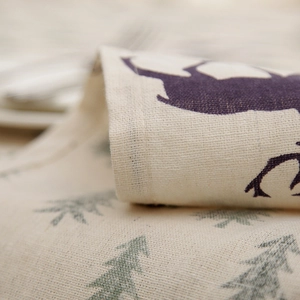 Detailed macro view of beige linen fabric with reindeer and Christmas tree print patterns