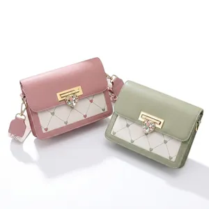 Détail du sac bandoulière avec boucle cœur et sangle à motifs en vert sauge et rose