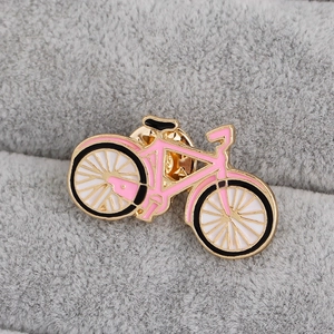 Dettaglio della spilla a bicicletta in smalto rosa con lega dorata e ruote bianche
