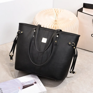 Detail of black pebbled leather tote bag featuring gold hardware and slim top handles