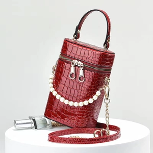 Dettaglio borsa a secchiello rossa in coccodrillo con catena di perle e doppia cerniera