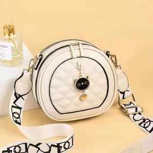 Sac à bandoulière rond matelassé beige avec pendentif chat noir et large sangle tissée
