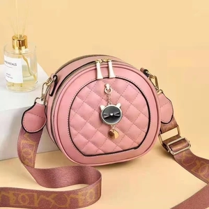Détail du sac bandoulière rond rose avec breloque chat en métal et large bandoulière