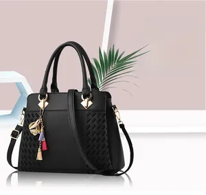 Détail d'un sac bandoulière noir avec texture litchi et pompon décoratif à fleurs