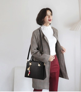 Détail du sac à main en cuir noir avec texture latérale tissée et pompon coloré élégant