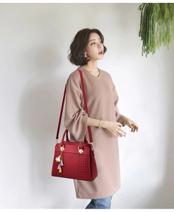 Vue détaillée du sac bandoulière en cuir rouge avec texture tressée et pompon coloré
