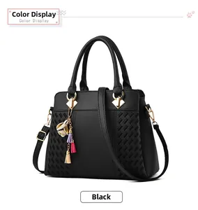 Détail du sac cabas en cuir PU noir avec texture matelassée et breloque à pompon floral