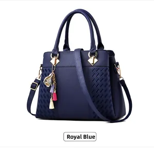Détail du sac à main bleu roi en cuir avec motif embossé et pendentif fleur à pompons