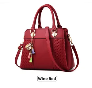 Détail d'un sac à main bordeaux en similicuir grainé avec texture tressée et pompon