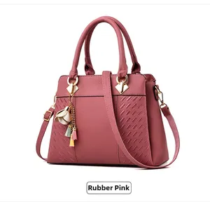 Détail du sac bandoulière rose poudré avec texture litchi et pompon floral