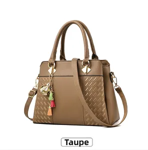 Détail macro du sac bandoulière ocre avec texture grainée et pompons colorés élégants