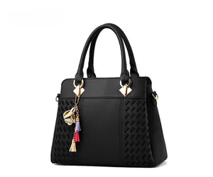 Détail du sac à main en cuir grainé noir avec texture tressée et pompon décoratif
