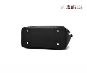Détail du fond d'un sac à main en cuir grainé noir avec quatre pieds de protection dorés