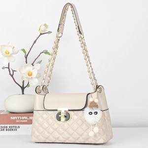 Detail of quilted texture, gold metal lock, and white plush charm on a pink handbag