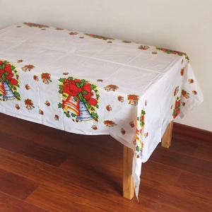 Détail de nappe de Noël jetable avec nœuds rouges, cloches bleues et motifs houx