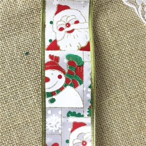 Close-up of white Christmas ribbon with gold edges, snowman and Santa Claus patterns