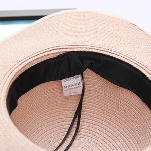 Detail view of straw hat inner label showing 100% paper material and 57cm size