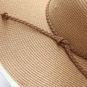 Close-up of straw sun hat featuring detailed woven texture and a knotted brown ribbon