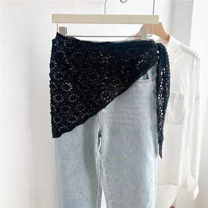 Detailansicht eines schwarzen Häkel-Schals mit Blumenmuster über einer Jeanshose