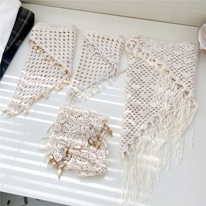 Close-up of bohemian beige crochet triangle scarves with wooden beads and tassel details