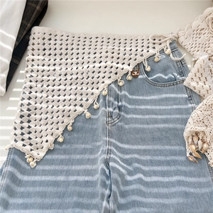 Boho crochet triangle waist belt with wooden beads layered over denim jeans
