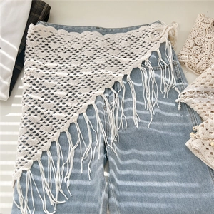 Handmade crochet cotton triangle scarf with fringe tassels over denim pants