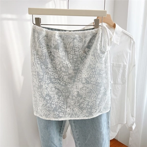 Detailed view of white floral lace layering skirt with side tie over blue jeans