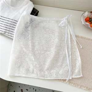 Detail of white floral lace layering skirt with delicate embroidery and waist tie