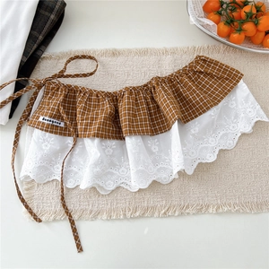 Détail d'une jupe superposée à carreaux marron avec bordure en dentelle blanche brodée