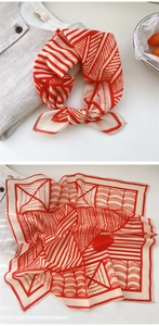 Detail of red and cream geometric cotton scarf showing textured weave and artistic print