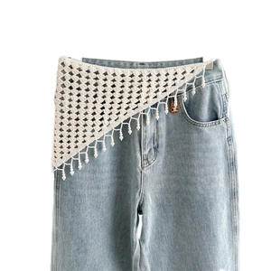 White crochet triangular waist wrap with tassel fringe over jeans for bohemian style