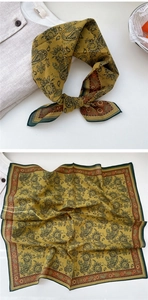 Detail of mustard yellow paisley cotton square scarf with dark green hem and knot styling