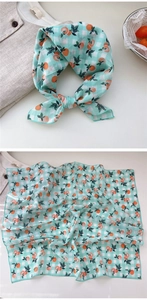 Detail of a mint green checkered square scarf featuring vibrant orange peach patterns