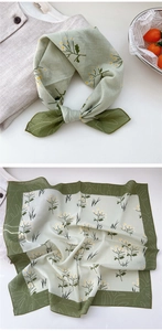 Close-up of light green floral cotton square scarf with daisy print and dark green border