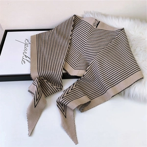 Elegant beige and black striped knitted scarf in soft cashmere-like fabric on white fur