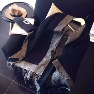 Détail d'un châle noir avec bordure en jacquard chevrons et franges sur une chaise