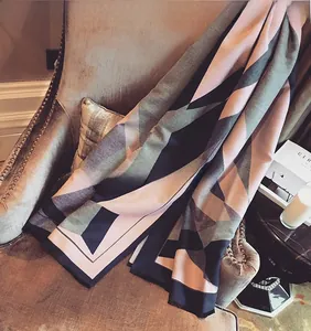 Detail of color-block geometric scarf with tassels on a vintage velvet chair