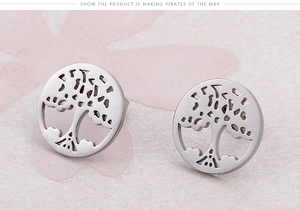 Macro shot of silver Tree of Life stud earrings with cutout design on pink floral background