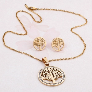 Golden tree of life necklace and earrings jewelry set with crystals on pink background