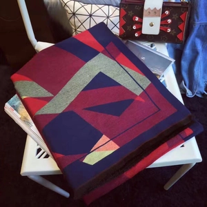 Detail of color-block geometric shawl with tassels on a chair, winter cashmere style
