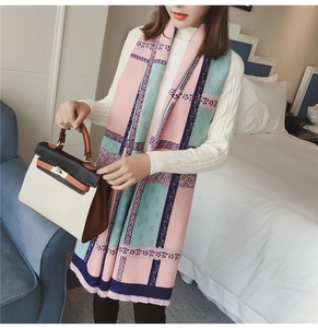 Detail of color-block knit scarf with geometric patterns and fringe edges on model