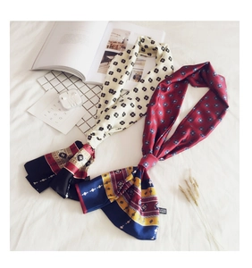 Detail of two retro geometric long silk scarves with ethnic patterns on white linen