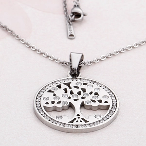 Silver stainless steel necklace with crystal tree of life pendant on pink textured background