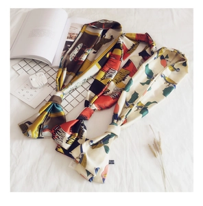 Detail of satin silk scarves featuring parrot, zebra, and geometric prints on white background