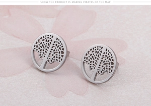 Macro view of silver tree of life earrings on a pink floral background