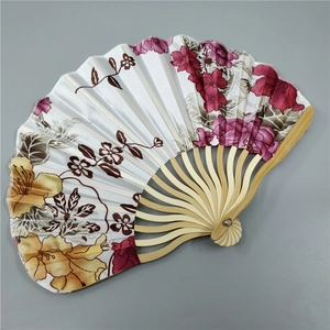 Close-up of a Japanese folding fan with bamboo ribs and colorful floral fabric patterns