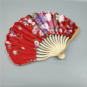 Detail view of a red silk folding fan with purple floral patterns and bamboo ribs