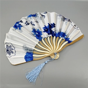 Detail of white fabric folding fan with blue floral patterns and bamboo ribs