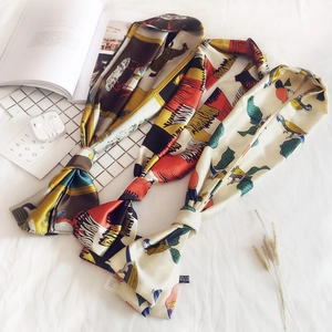 Three elegant patterned silk twilly scarves displayed with lifestyle accessories on white fabric